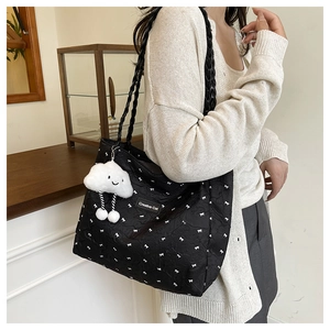 Close-up of black quilted tote bag with white bow prints and cloud charm detail