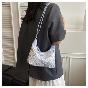 Close-up of light blue ethnic embroidery patterns and beaded zipper on underarm tote bag