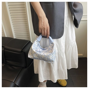 Macro view of geometric embroidery patterns and soft blue leather handles on the tote