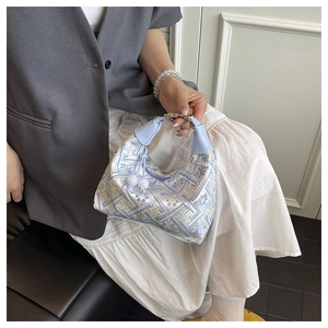 Detail of light blue embroidered handbag with floral motifs and leather ring handle
