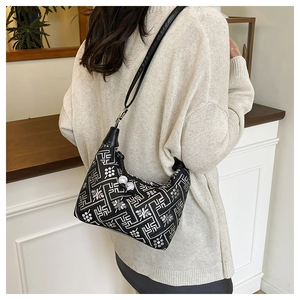 Detail of embroidered shoulder bag with white bead charms on a soft knitted sweater