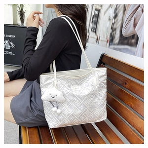 Dettaglio della borsa tote bianca con trama floreale geometrica e ciondolo a nuvola morbida