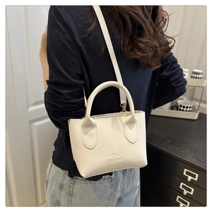 Close-up of cream textured leather bucket bag showing grain finish and handle details