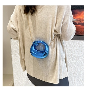 Detail of high-gloss blue metallic doughnut mini bag with delicate gold chain strap