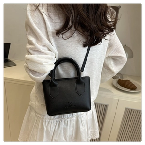Close-up of black litchi grain leather handbag with dual handles and metal buckle detail