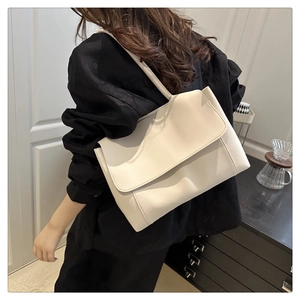Detailed back view of a cream leather tote bag styled on a person in a minimalist interior