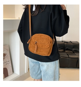 Detail of yellow corduroy crossbody bag featuring woven zipper and adjustable strap