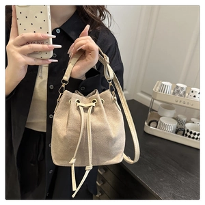 Beige suede drawstring bucket bag with adjustable strap shown in a daily mirror selfie
