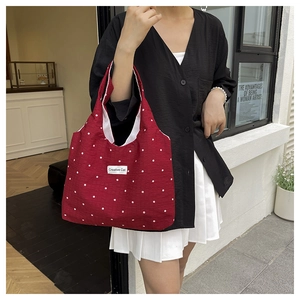 Detalle del bolso tote de lona roja con lunares, etiqueta de marca y textura de tela
