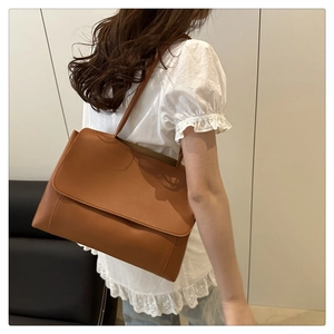 Caramel brown leather tote bag worn by a model, showcasing large capacity and elegant style