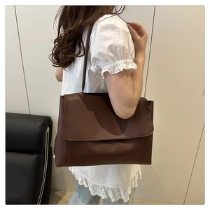 Detail view of large dark brown PU leather tote bag worn as a shoulder bag on model