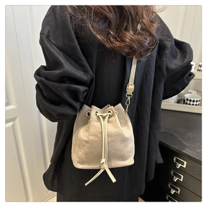 Detail of beige drawstring bucket bag with gold-tone hardware and adjustable strap