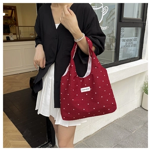 Detalle del bolso tote burdeos de lona con flores y etiqueta de marca Creative Cat para