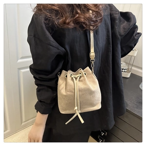 Close-up of apricot suede bucket bag with drawstring closure and golden hardware