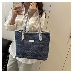 Détail du sac cabas en denim à pois bleus avec des poignées en similicuir argenté