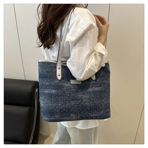 Detail of denim tote bag with pearl chain strap worn by model for casual summer style