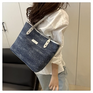 Detail of denim blue tote bag with white star pattern and fashion leather nameplate