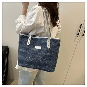 Close-up of blue denim tote bag with white polka dots and silver faux leather handles