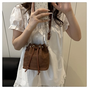Detailed mirror selfie showing dark brown suede bucket bag with drawstring closure