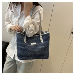 Détail du sac cabas en denim avec paillettes argentées et logo métallique sur l'anse