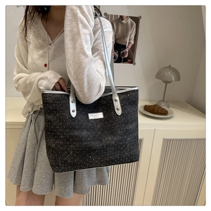 Détail des rivets argentés et ferrures sur un sac cabas noir à pois blancs élégant