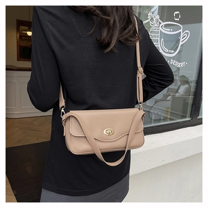 Schicke beige Leder-Umhängetasche mit ovalem Goldschloss getragen von einem Model