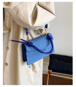 Close-up of royal blue woven crossbody bag with geometric texture and gold metal hardware
