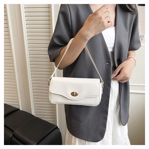 Detailaufnahme der weißen Achseltasche mit goldener Schnalle und modernem Wellendesign