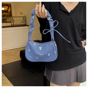 Détail du sac en jean bleu avec imprimé floral rose et bandoulière élastique froncée