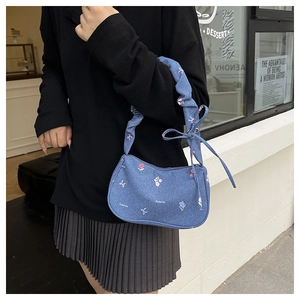 Gros plan du sac plissé en denim bleu avec imprimés floraux et détails de nœuds