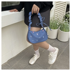 Détail d'un sac en denim avec broderies florales et anse froncée au design de nuage