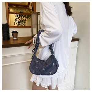 Détail du sac hobo en jean bleu avec motif nœud blanc et bandoulière nouée élégante