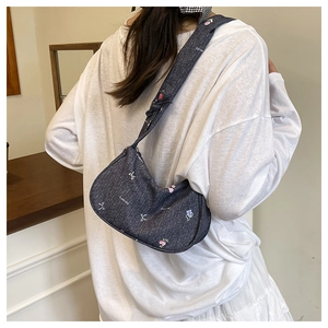Détail du sac demi-lune en denim bleu avec broderies florales et nœud blanc élégant