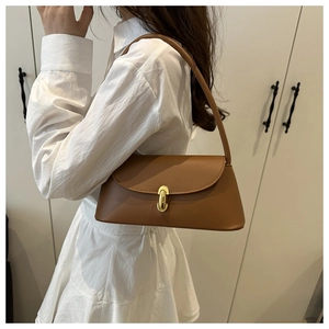 Detail view of caramel brown baguette bag featuring a gold twist lock and smooth texture