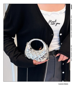 Mini silver crescent moon handbag with quilted texture and metal chain strap worn by model