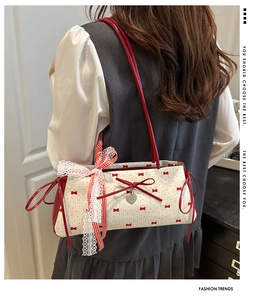 Detailed view of lace trim, red gingham bow, and heart pendant on white tote bag