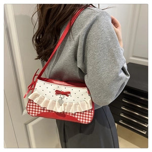 Detail of red and white plaid shoulder bag with delicate silk ruffle and heart pendant
