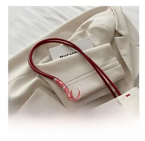 Detail of white tote bag with red bow pattern, lace trim, and silver heart pendant