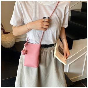 Detail of pink lychee leather mini crossbody bag with knot ball pendant on a model