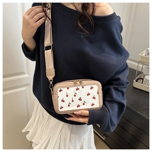 Dettaglio della borsa tote albicocca trendy con stampe ciliegia e tracolla in nylon