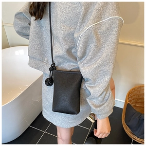 Detail of minimalist black pebbled leather mini crossbody phone bag with knot strap detail