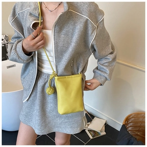 Close-up of a bright yellow litchi pattern leather mini phone bag with knotted strap