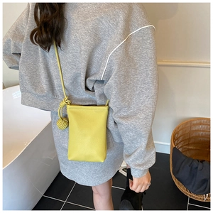 Detail of bright yellow crossbody phone bag with pebble leather texture and knot strap