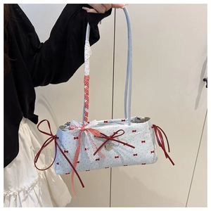 Close-up of light blue tote bag with red bow print and delicate lace handle detail
