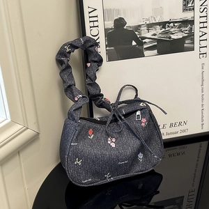 Sac sous le bras en jean avec broderies florales et anse froissée sur surface miroir