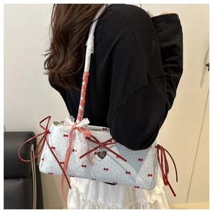 Detailed side view of tote bag with red bow prints and white lace fringe tassel detail