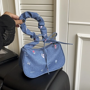 Sac à main en denim bleu avec fleurs, poignée froncée et nœud dans un décor chaleureux