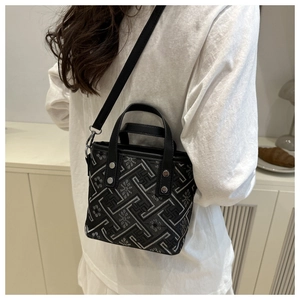 Model wearing a geometric jacquard crossbody bag with black leather trim in a home setting