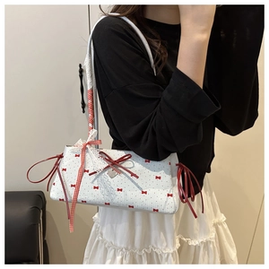 Detail of white lace tote bag with red bow patterns and heart-shaped metal pendant