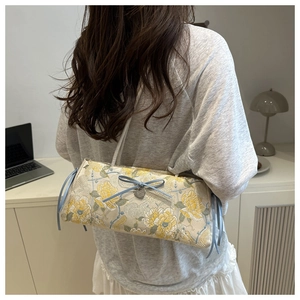 Detail of floral jacquard embroidery on cream shoulder bag with heart metal charm